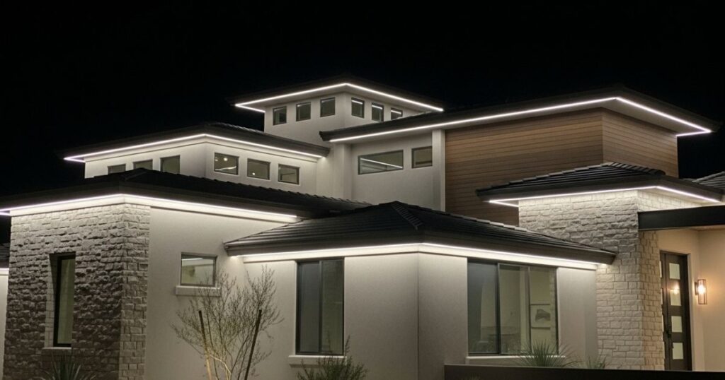 Roofline and eave lighting casting a soft glow on a modern desert-style home at night.